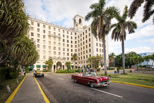 Havana, Cuba - January 21, 2017: A red vintage convertible car with tourists passing the hotel Nacional de Cuba in Havana.