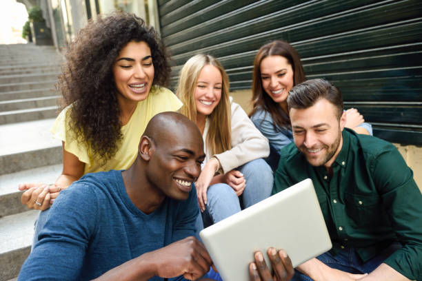 multiethnische gruppe junger menschen, die sich einen tablet-computer ansehen - computer student mixed race person multi ethnic group stock-fotos und bilder