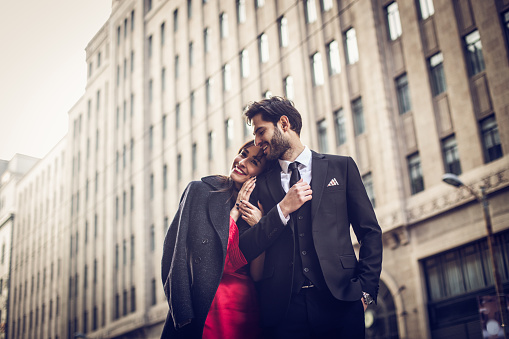 Elegant dressed couple in love walking down the street early in spring.