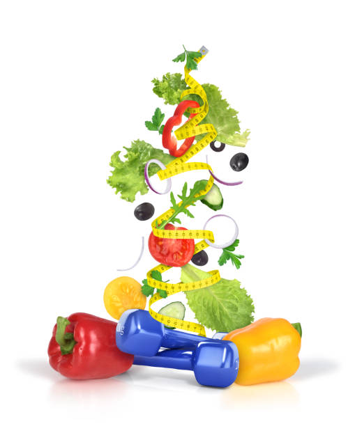 istock Dumbbels and measuring tape with flying vegetables isolated on white background 690440320