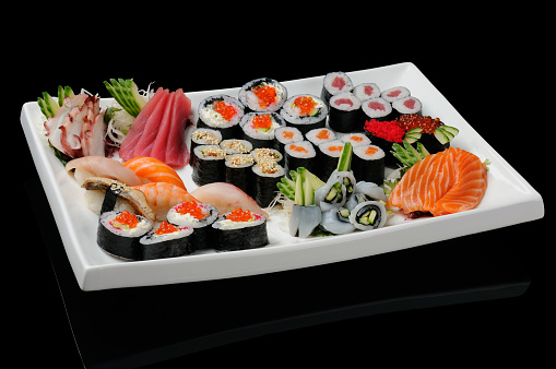 Assortment of rolls, sushi and sashimi served on white plate