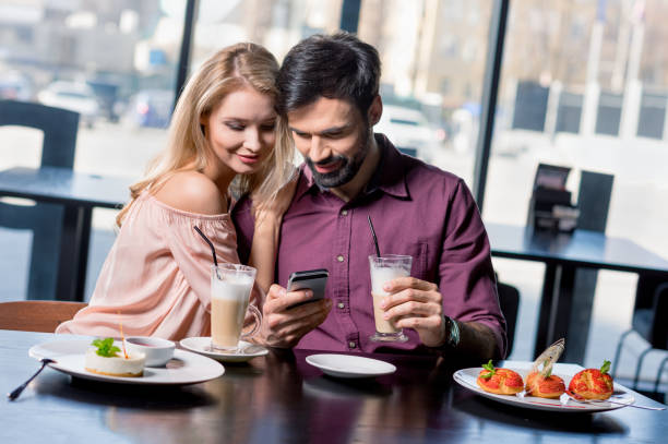 istock romantic couple in love using smartphone on coffee break in restaurant 690452246