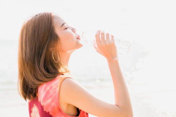 istock Young woman drinking water on the background is a beautiful white water reflection. 690464664