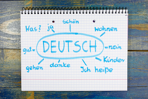 concept of learning german (deutsch) language. basic vocabulary written in notebook on wooden background