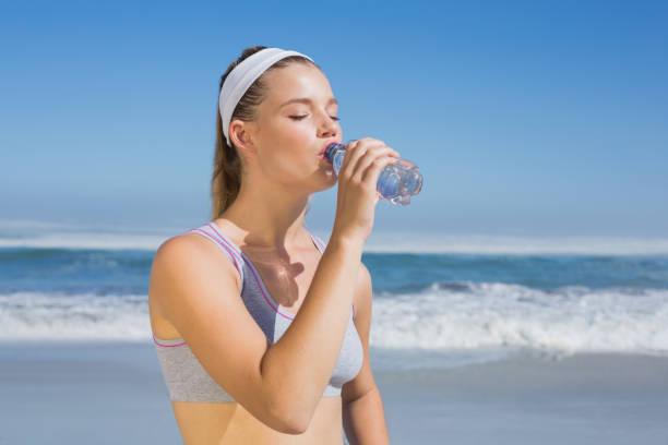 istock Sporty blonde drinking water on the beach 690478718