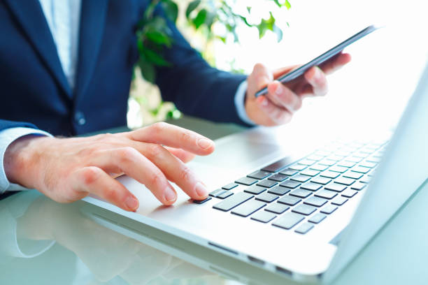 istock Men office worker typing on the keyboard and using smartphone 690478932