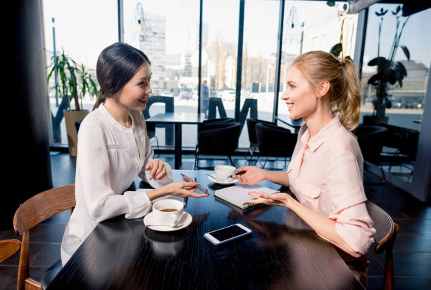 istock Smiling young businesswomen looking at notebook and discussing project at coffee break 690479086