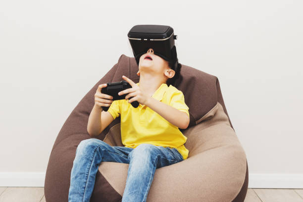 istock Boy plays game with virtual reality glasses indoors 690486740