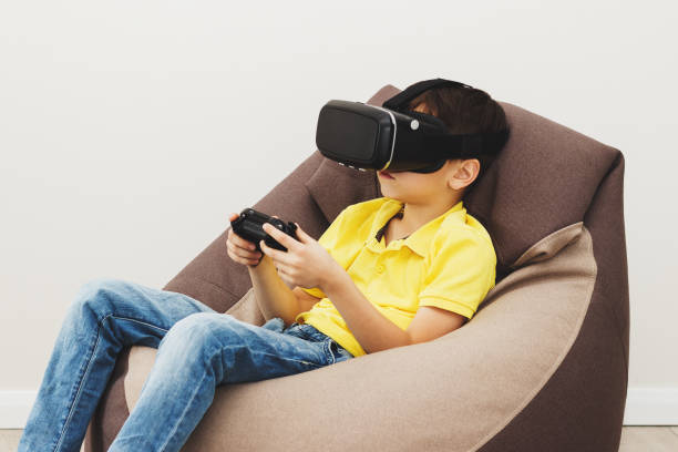 istock Boy plays game with virtual reality glasses indoors 690489402