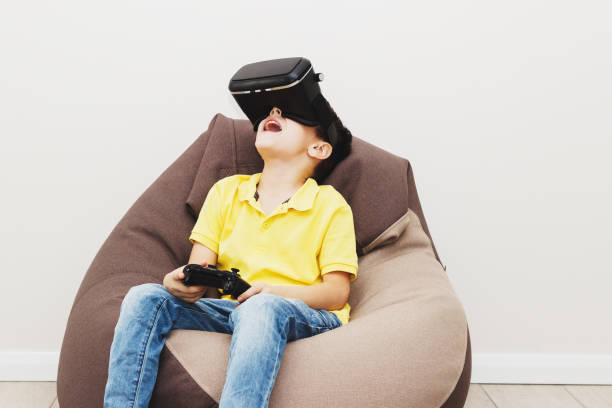 istock Boy plays game with virtual reality glasses indoors 690489834