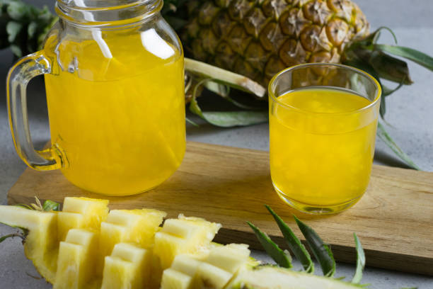 istock Glass of Pineapple juice with jar on a stone table. 690493680