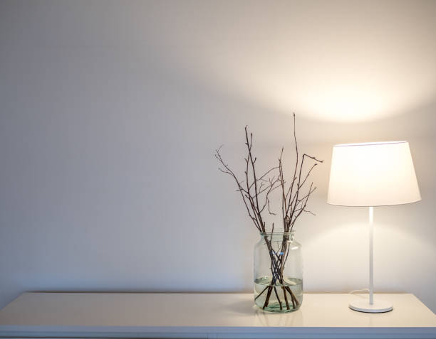 istock White lamp and twig vase on bureau. White wall in background. Scandinavian design. 690500822