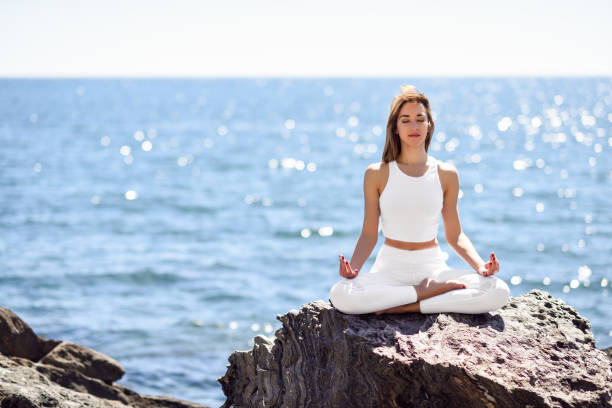 istock Young woman doing yoga in the beach 690511222