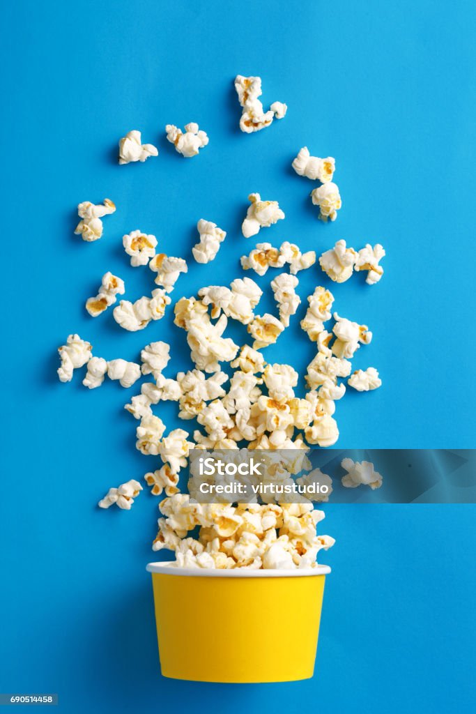 Palomitas de maíz. Lay Flat de taza palomitas de maíz sobre un fondo azul. Vista superior - Foto de stock de Palomitas libre de derechos