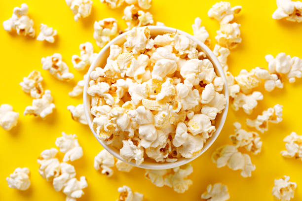 istock Popcorn viewed from above on yellow background. Flat lay of pop corn bowl. Top view 690514632