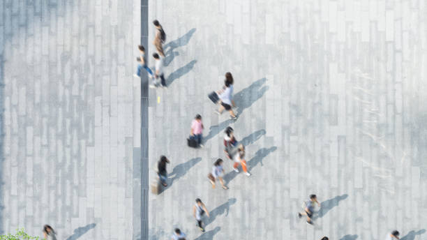 istock blur process of people walk on across the pedestrian concrete landscape with dark shadow on the floor (wide angle of aerial top view) 690517536