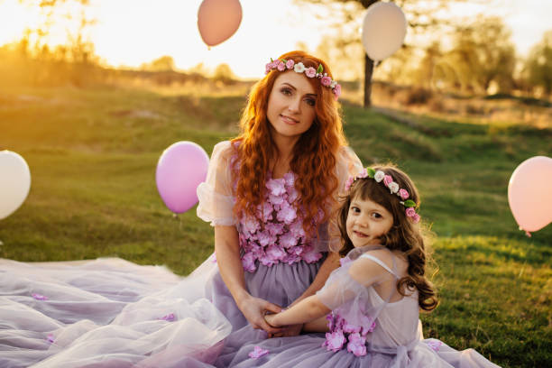 junge rothaarige mutter mit ihrer tochter auf die natur in der sonne ausruhen - sun sky child balloon stock-fotos und bilder