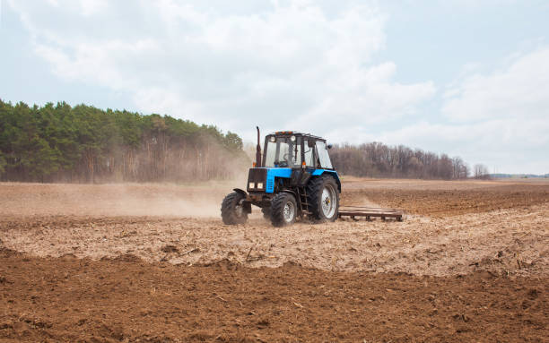 istock spring day the tractor goes and pulls a plow plowing a field before landing of crops 690529374