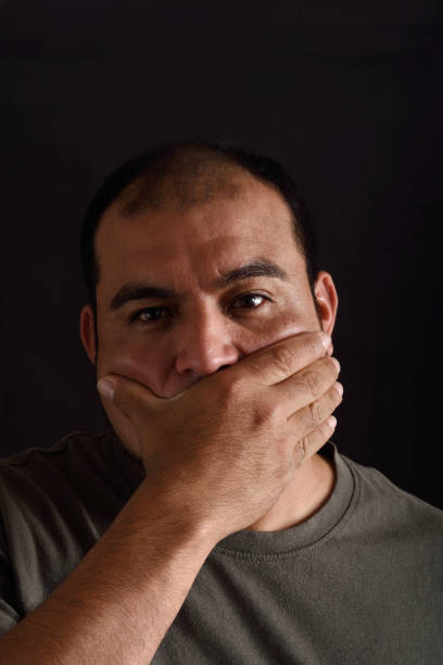 istock Man covering his mouth on black background 690532782