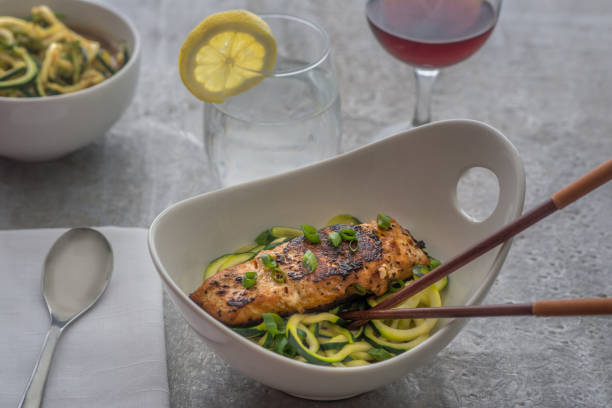 Grilled salmon over a bed of zoodles place setting with wine glass, water glass and side dish