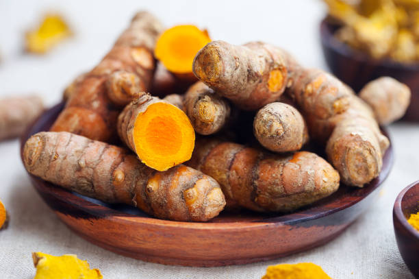 Fresh and dried turmeric roots in a wooden bowl. stock photo