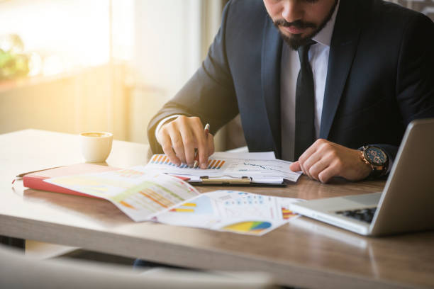 joven empresario que muestra gráficos de pluma - analyzing chart scrutiny planning fotografías e imágenes de stock