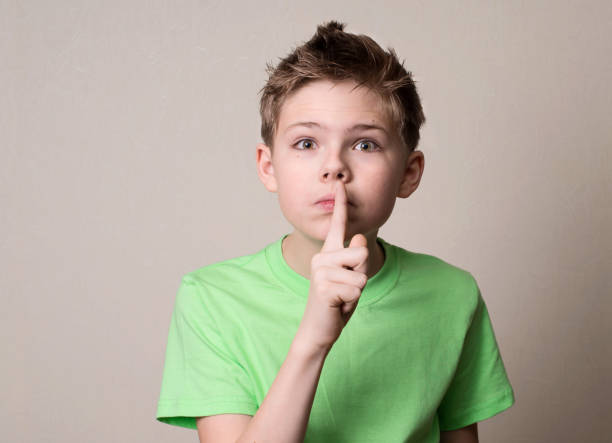 istock Scared boy doing a silence gesture. Kid putting finger up to lips and ask silence. 690577506