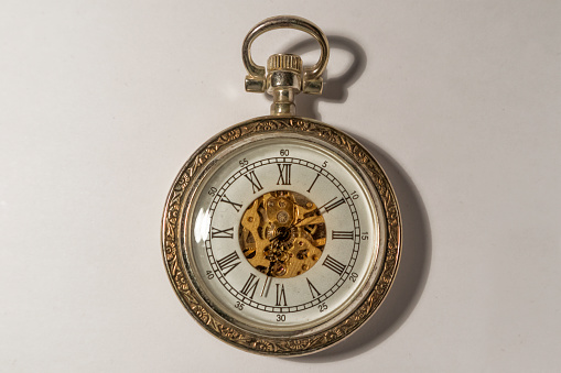 Horizontal close up of part of antique table clock in bronze metal with intricate detailed design sitting in rural country hallway Australia