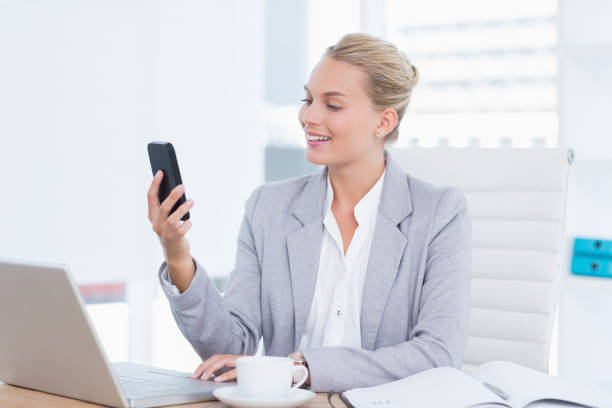 istock Smiling businesswoman sending a text at her desk 690587872