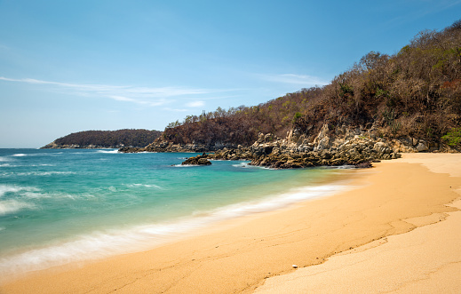 Long exposure of a beach by the Pacific Ocean during daytime in one of the nine bays of Huatulco in the state of Oaxaca, Mexico.