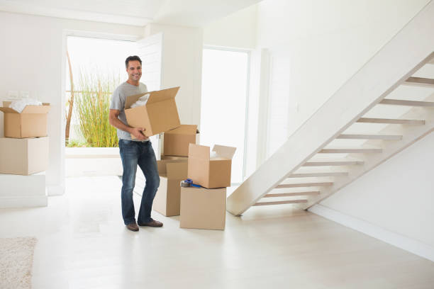 istock Smiling man carrying boxes in a new house 690593636
