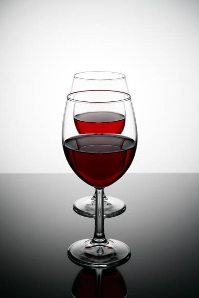 istock Two glasses of red wine with drops and reflections on a glass table. 690593716