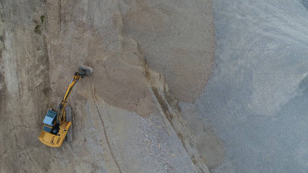 Aerial view of a gravel pit with yellow bulldozers. Picture made with a drone.