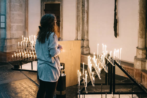Young girl lighting a candle in a Catholic church in Rocamadour and placing it amongst a line of other candles