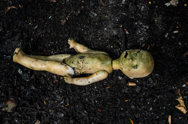 Old broken doll on the pile of the ash