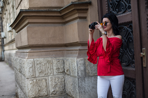 Fashionable female tourist with camera in the city.