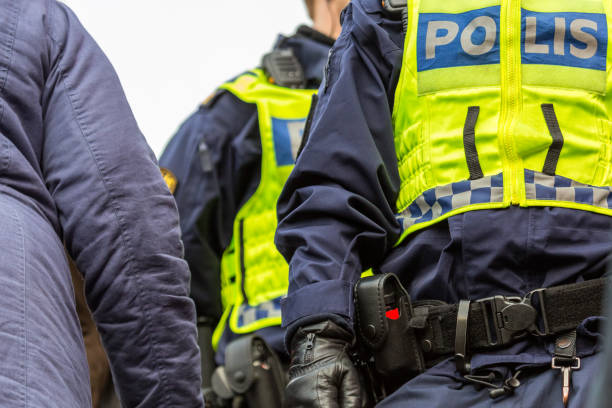 Two police officers in a crowd, close up of upper body with vest and equipment belt. stock photo