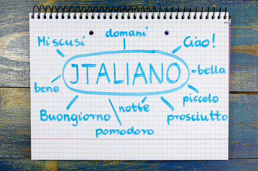 concept of learning italian (italiano) language. basic vocabulary written in notebook on wooden background