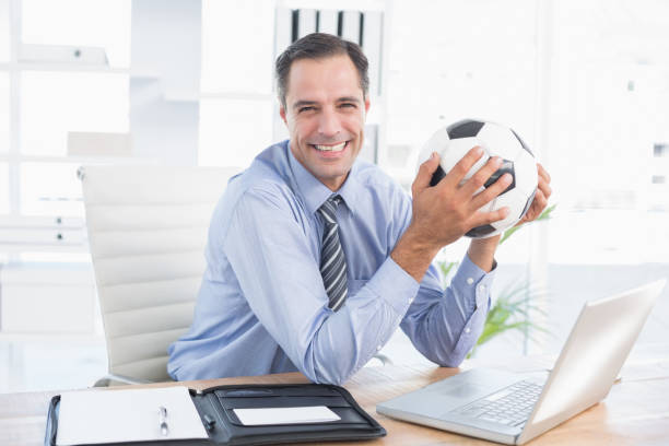 istock Smiling businessman looking at camera with foot ball 690636230