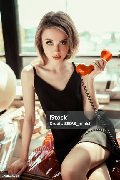 Close Up Portrait Of A Beautiful Young Woman With Retro Red Telephone  Sitting On Table Girl With Nude Make Up Fashion Eyebrow And Green Eyes  Beauty Concept Vintage Style Stock Photo -
