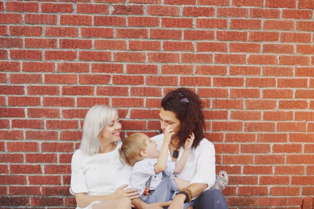 beautiful young family dad mom and a little boy with blond hair walking around the city and enjoying the sunshine, multi family black and white three way kiss stock pictures, royalty-free photos & images