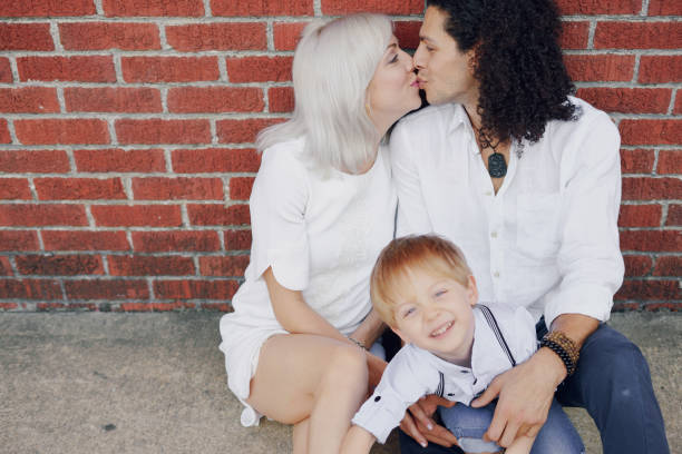 beautiful young family dad mom and a little boy with blond hair walking around the city and enjoying the sunshine, multi family black and white three way kiss stock pictures, royalty-free photos & images
