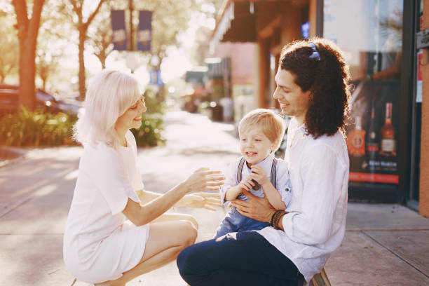 beautiful young family dad mom and a little boy with blond hair walking around the city and enjoying the sunshine, multi family black and white three way kiss stock pictures, royalty-free photos & images