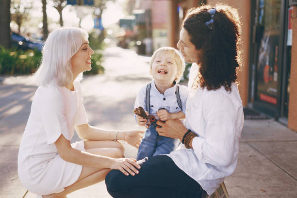 beautiful young family dad mom and a little boy with blond hair walking around the city and enjoying the sunshine, multi family black and white three way kiss stock pictures, royalty-free photos & images