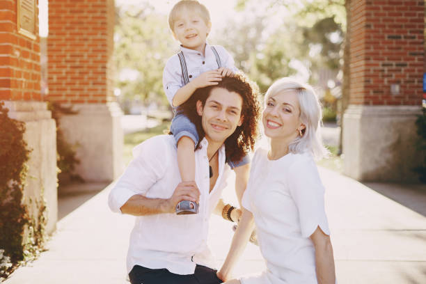 beautiful young family dad mom and a little boy with blond hair walking around the city and enjoying the sunshine, multi family black and white three way kiss stock pictures, royalty-free photos & images
