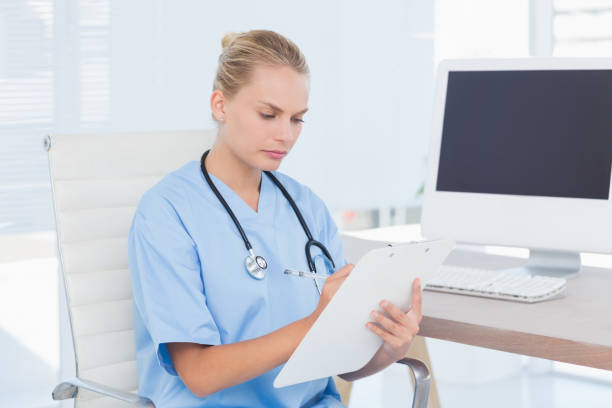 istock Concentrated nurse writing on clipboard 690639560