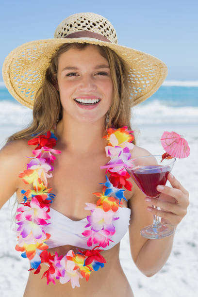 bonita rubia sonriente en guirnalda floral sosteniendo cóctel en la playa - instructor one person fruit drinking fotografías e imágenes de stock