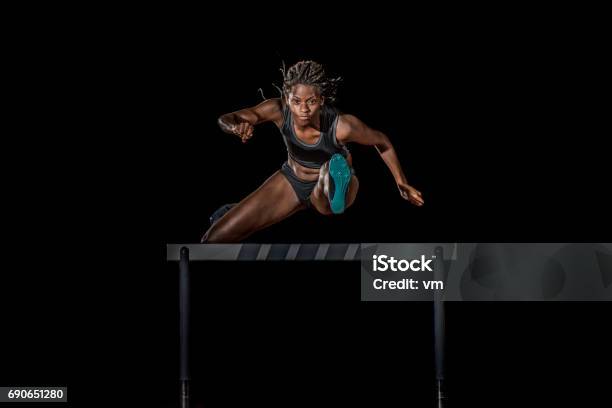 Female Athlete Jumping Over A Hurdle At Night Stock Photo - Download Image Now - Hurdling - Track Event, Track Starting Block, Running