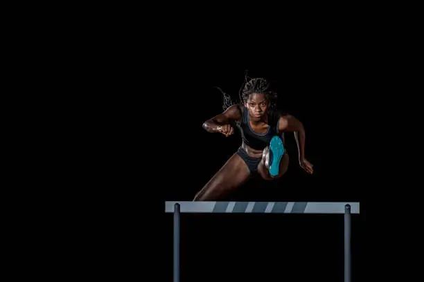 Photo of Female athlete jumping over a hurdle