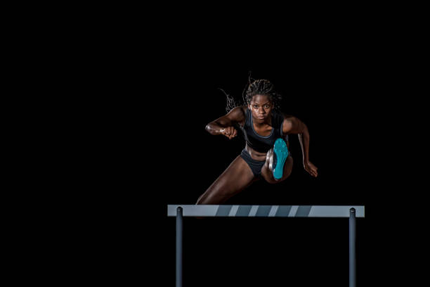 female athlete jumping over a hurdle - hurdling imagens e fotografias de stock